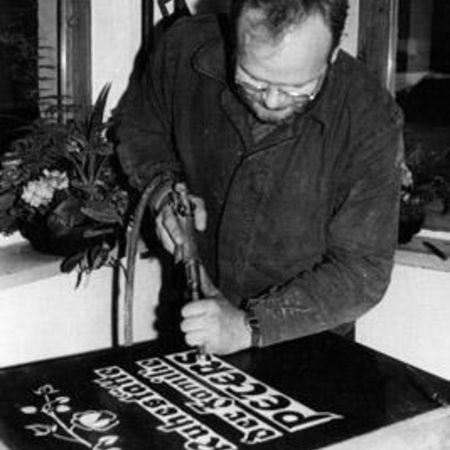 Schwarz-Weiß-Aufnahme eines Steinmetzmeisters bei der Arbeit